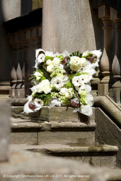 WHITE TEXTURED CUSHION - A textured cushion of white and green flowers.